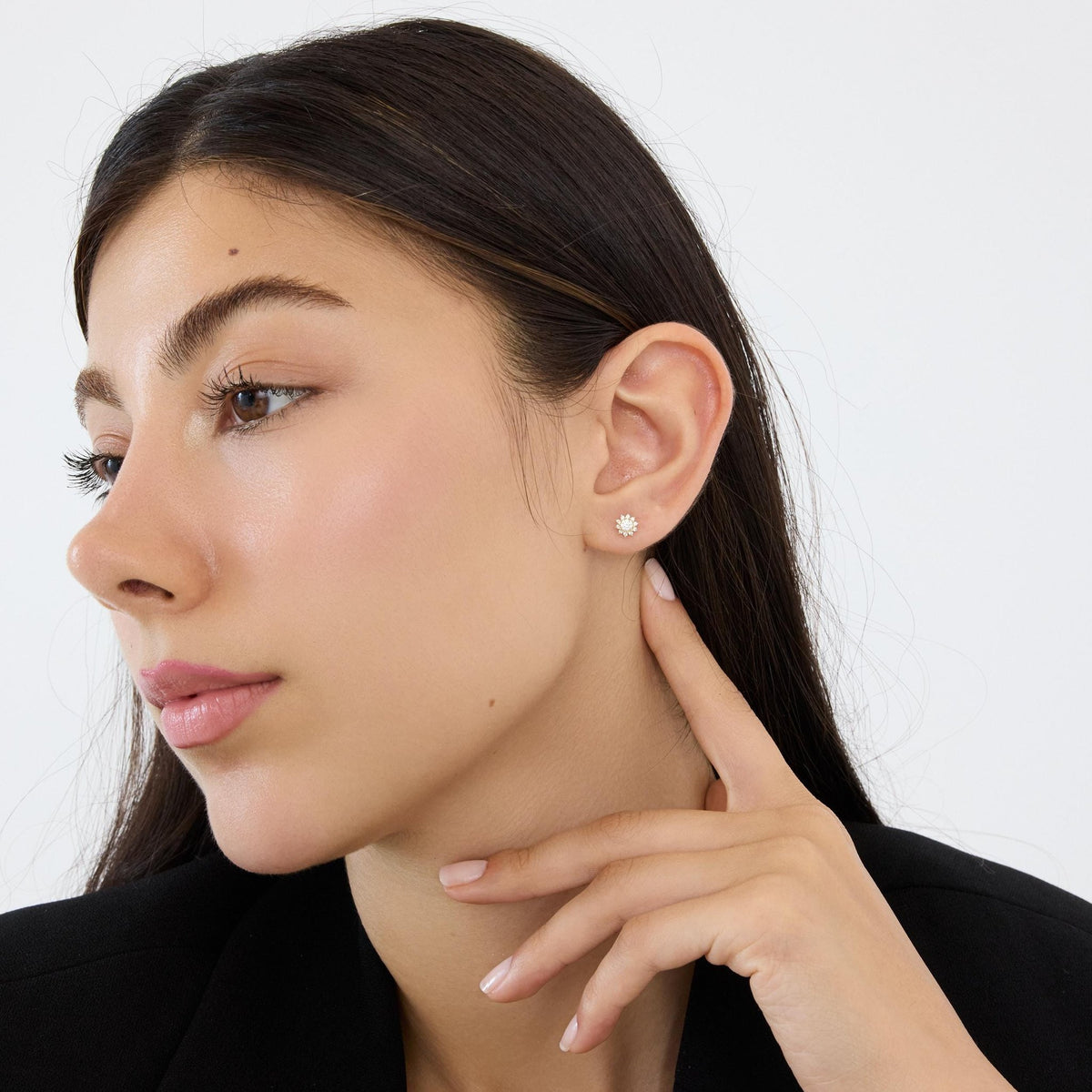 Woman in profile wearing a 14K gold cubic zirconia halo stud earring, hand resting at her neck