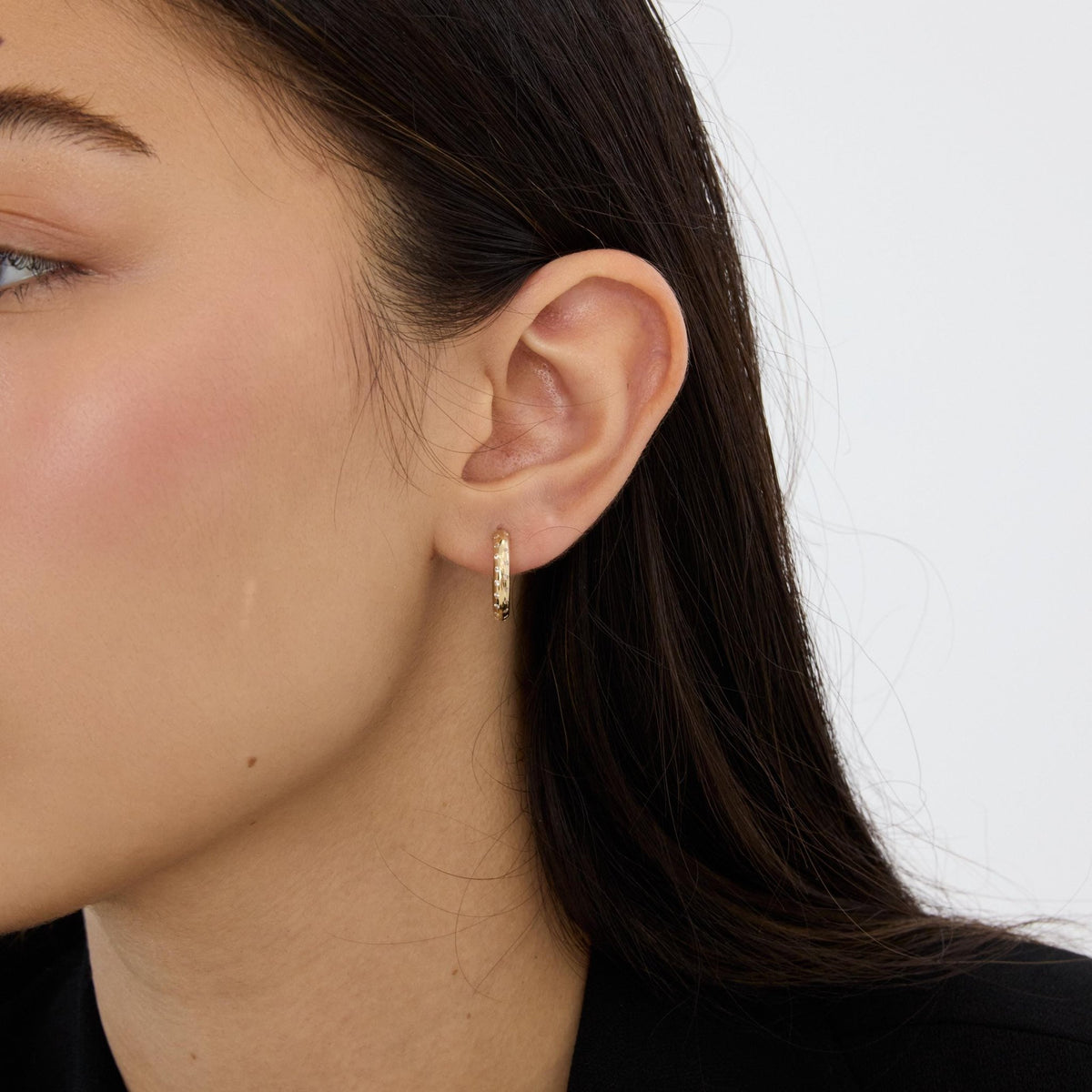 14K gold cubic zirconia hoop earring worn in earlobe, model's ear seen from the side, second angle