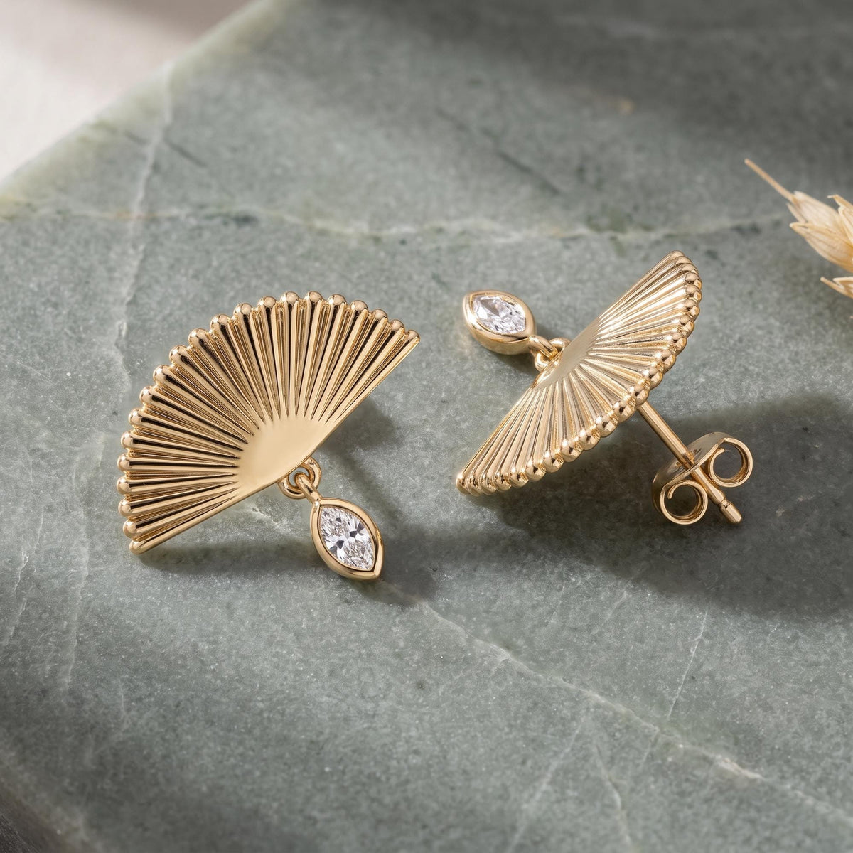 14K yellow gold fan drop stud earrings with marquise cubic zirconia, pair resting on grey-green stone