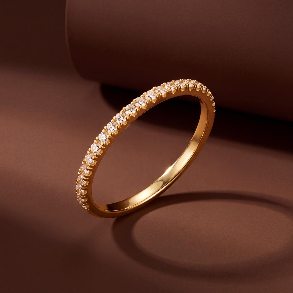 14K gold half eternity ring with cubic zirconia standing on edge against a dark brown backdrop