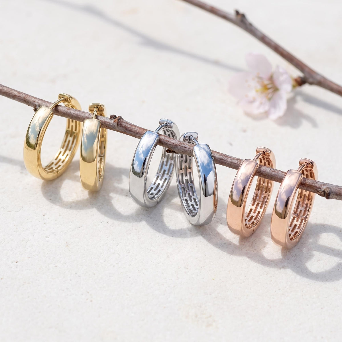 14K huggie hoop earrings in yellow, white and rose gold, three pairs hanging on a branch
