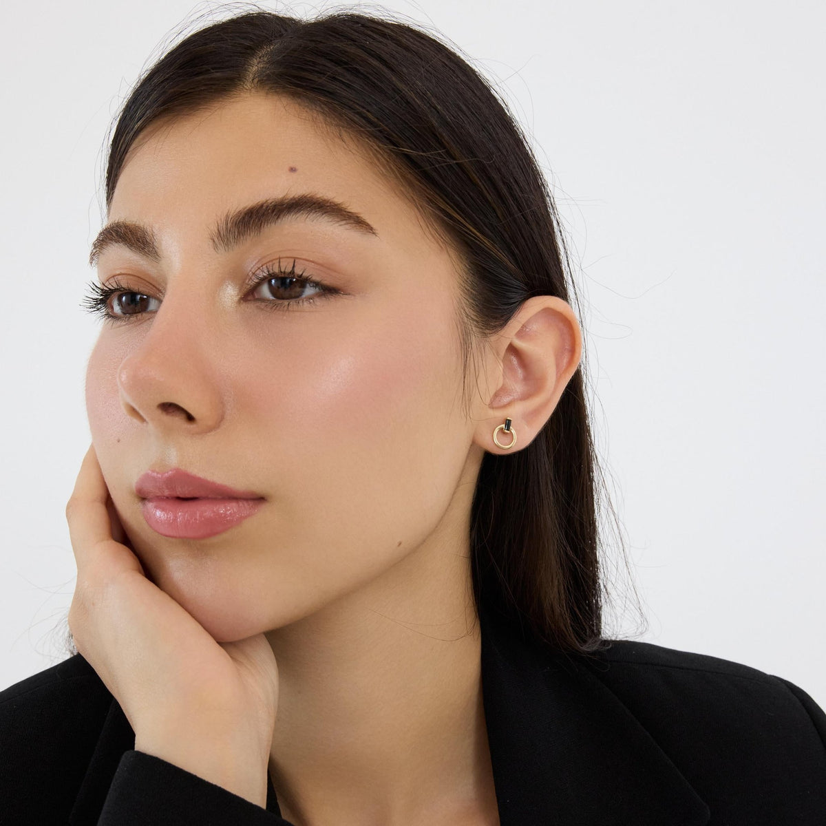 14K gold open circle stud earring with black stone on model's ear, her hand resting against her cheek
