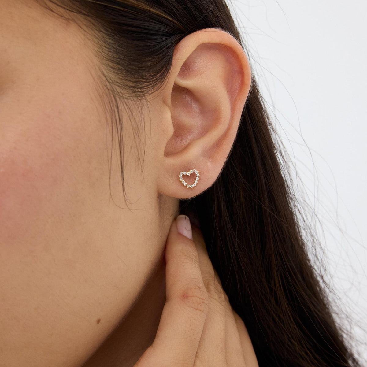 14K gold open heart stud earring with cubic zirconia worn on the earlobe, second ear close-up angle