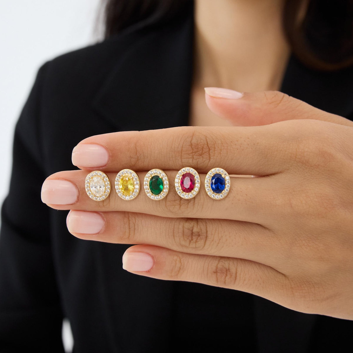 14K gold oval stud earrings in five stone colours on fingertips, third angle with hand held slightly lower