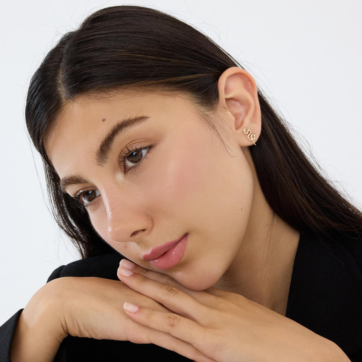 14K gold snake stud earrings styled on a neutral backdrop, third angle