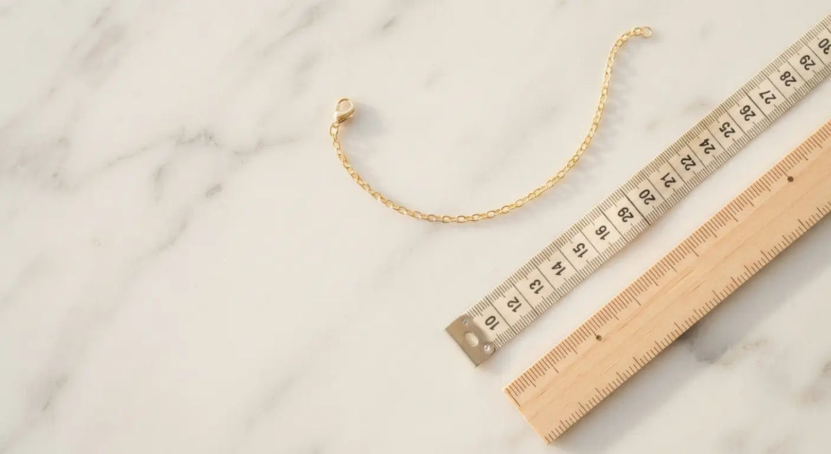 14K gold bracelet beside a measuring tape and ruler, illustrating how to measure wrist size