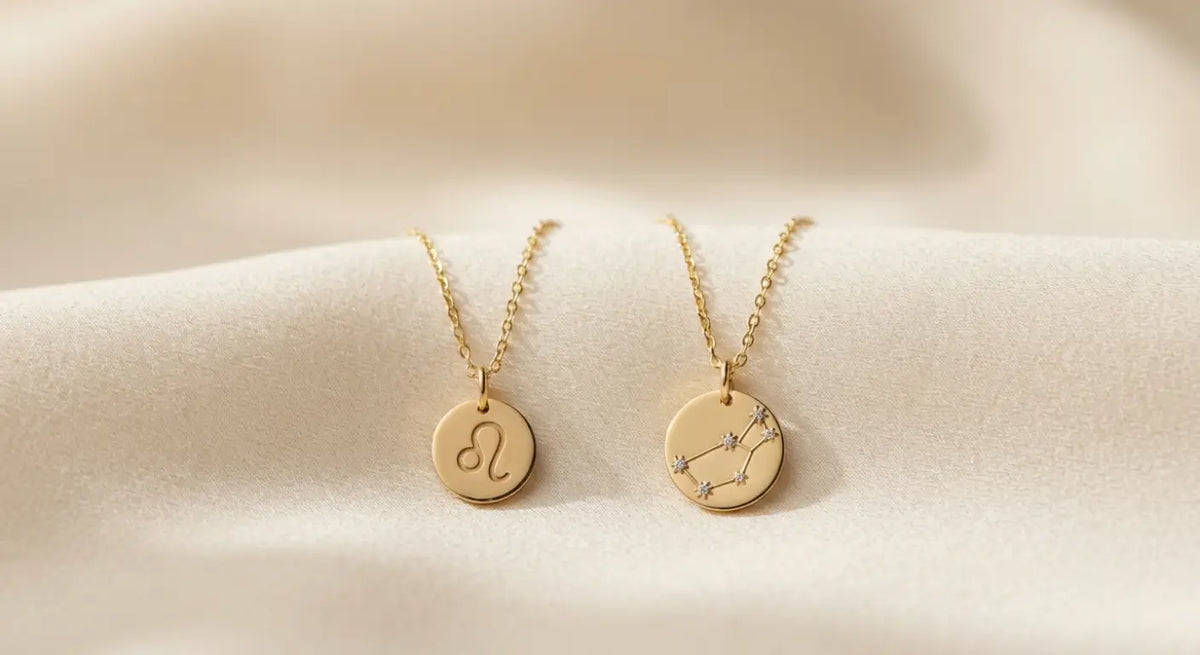 Two 14K gold zodiac pendant necklaces for Leo and Virgo, the August star signs, on cream silk