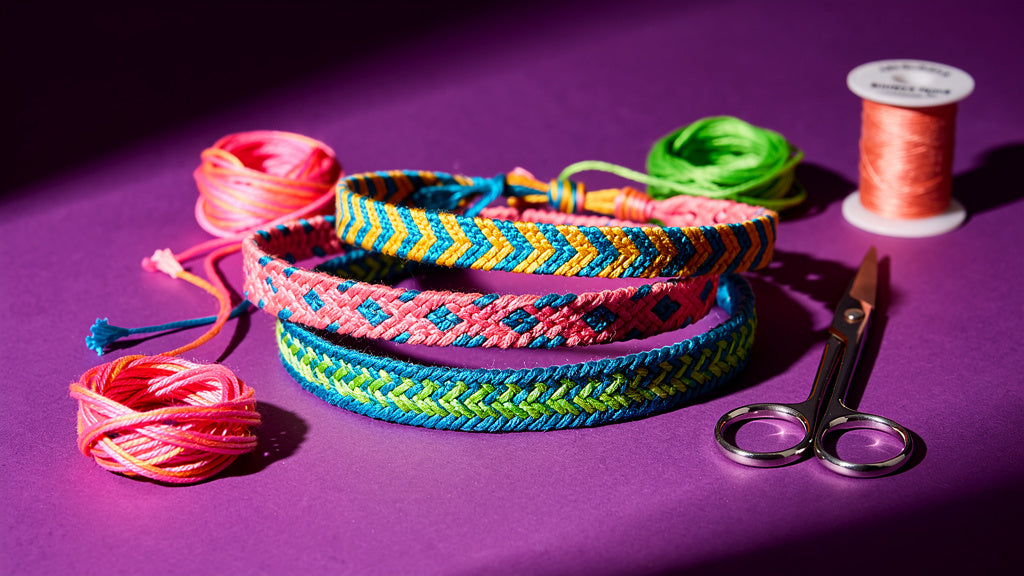 Handmade friendship bracelets in different patterns next to embroidery floss