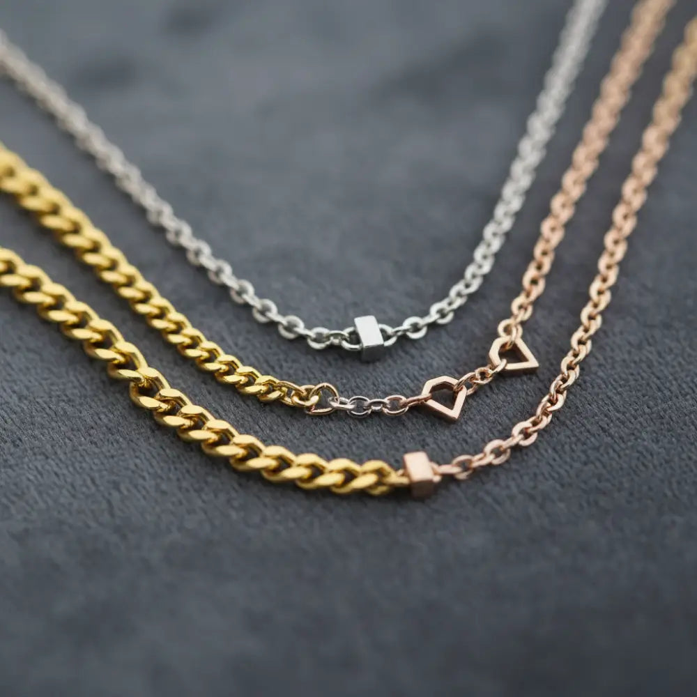 Yellow, white, and rose gold necklaces with chain links on dark background