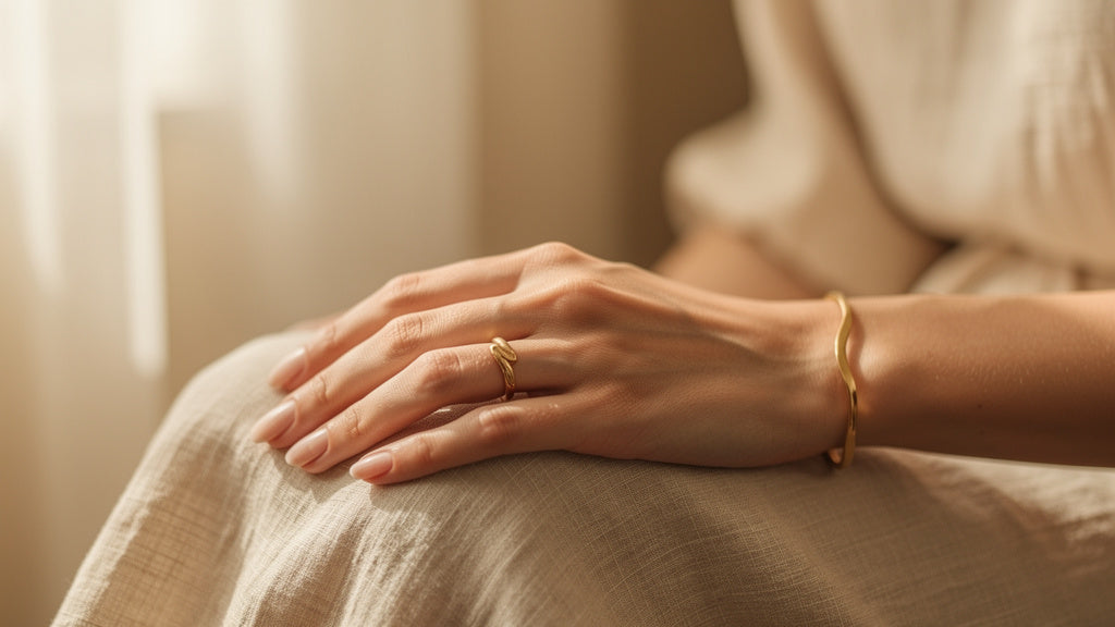 Hand wearing warm gold jewelry, illustrating the difference between 10k vs 14k gold