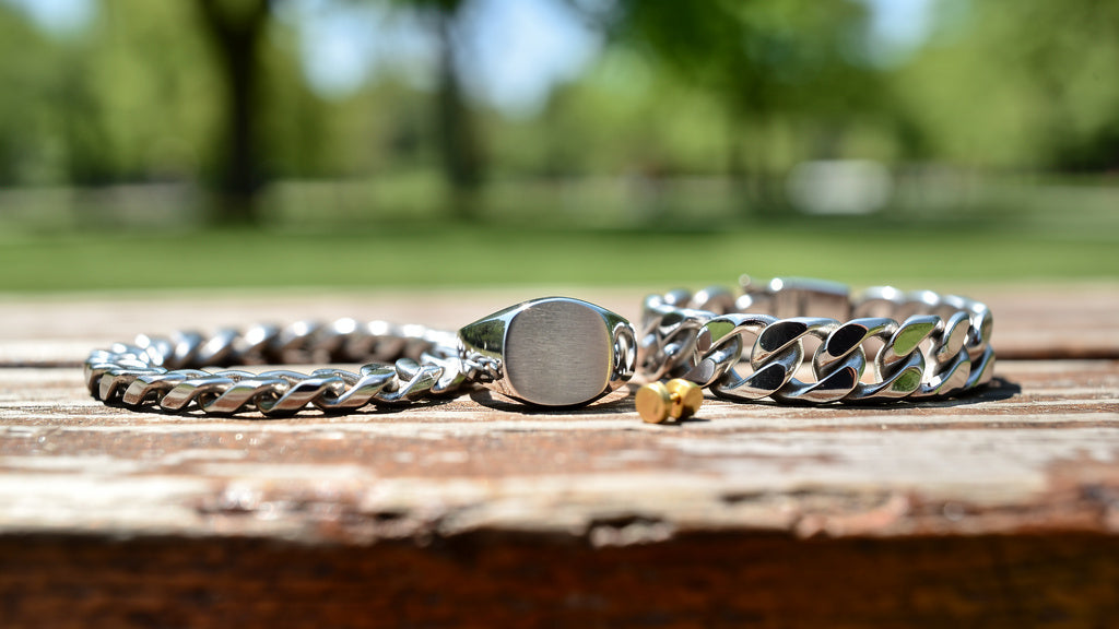 Men's jewelry collection with a gold chain, signet ring, bracelet, and stud earring