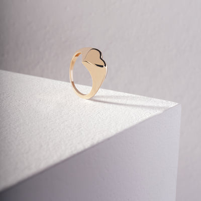 Gold heart ring with a unique design on a light gray background