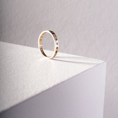 Gold ring with colored stones on a light gray surface