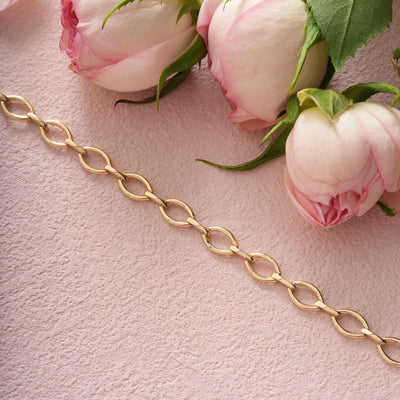 Gold chain on a pink surface with pink roses
