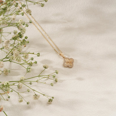 Gold necklace with a floral pendant on a light fabric background