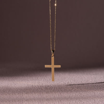 Gold cross necklace on a textured surface with a dark background
