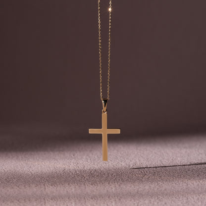 Gold cross necklace on a textured surface with a dark background