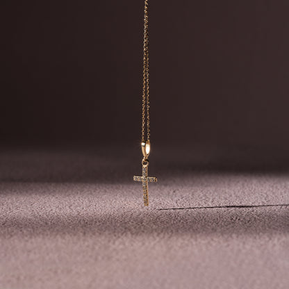 Gold cross necklace on a textured surface with a dark background