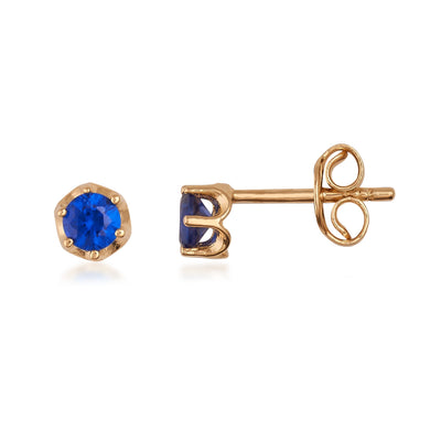 Gold stud earrings with round blue gemstone on white background