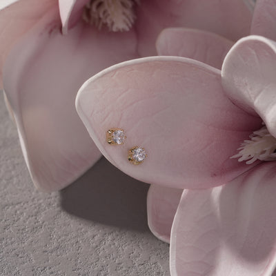 Gold stud earrings with clear gemstones on pink flower petals