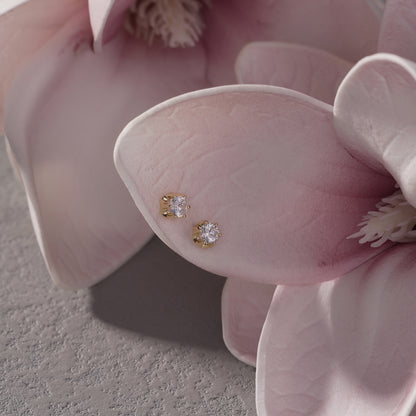 Gold and diamond earrings on a pink flower
