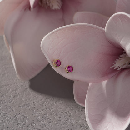 Pair of pink gemstone earrings on a pink flower