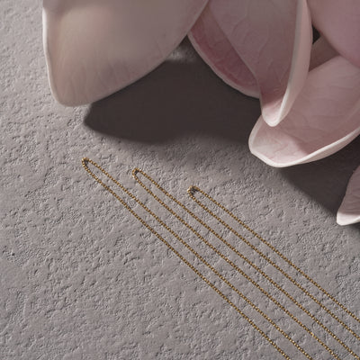 Pink ceramic flower pot with gold leaf design on a textured gray surface