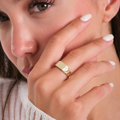 Close-up of a woman's hand with a gold ring on her finger, signet ring.