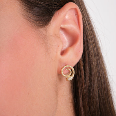 Gold spiral earring with textured design worn on ear, fine jewelry close-up