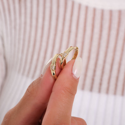 Hand holding two gold rings with diamonds, close-up jewelry photo