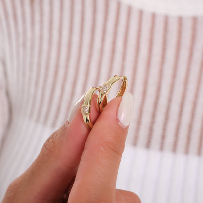 Gold ring with a diamond on a finger against a neutral background