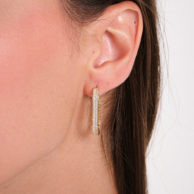 Close-up of a gold hoop earring with pavé stones worn on a woman's ear