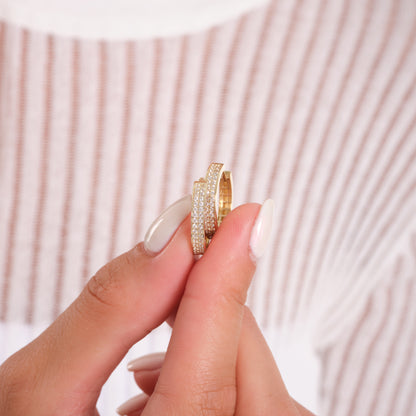 Gold ring with diamond accents held between fingers against a neutral background