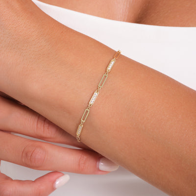 Gold bracelet with clear stones on a wrist against a white background