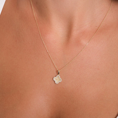 Gold necklace with a floral pendant on a person's neck