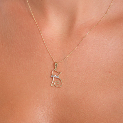 Gold cat-shaped pendant necklace on a person's neck
