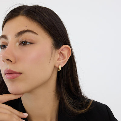 14K gold bamboo hoop earring with round cubic zirconia worn on the ear, woman in black blazer, side profile