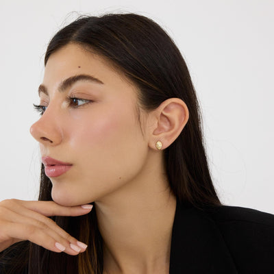 14K gold braided knot stud earring on woman in profile, hand under chin, black blazer