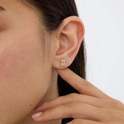 14K gold cluster stud earring with cubic zirconia worn on the ear, model touching the earlobe