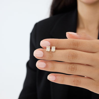 Pair of 14K gold cluster stud earrings with cubic zirconia held on a fingertip to show small size