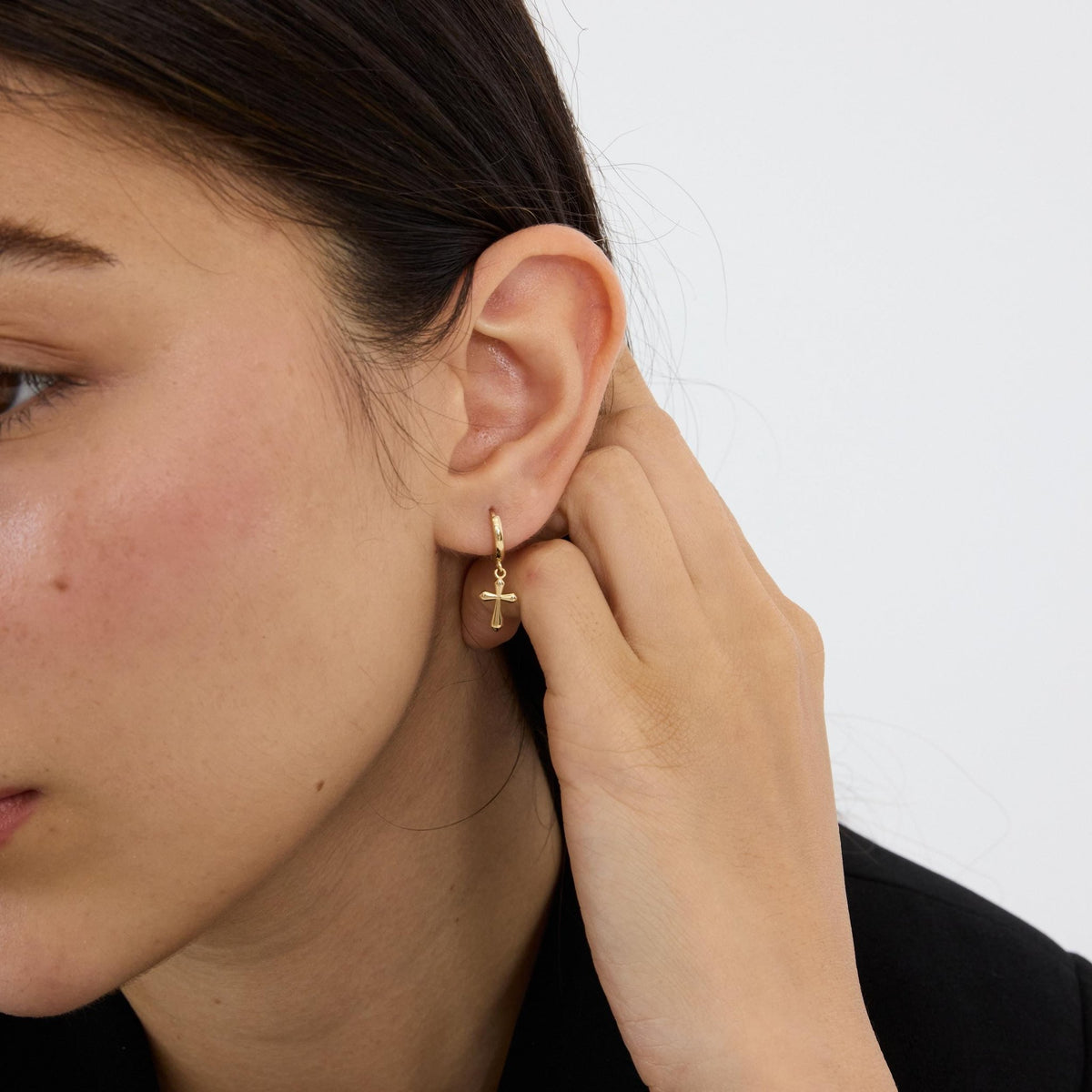 14K gold cross hoop earrings styled on a neutral backdrop, third angle