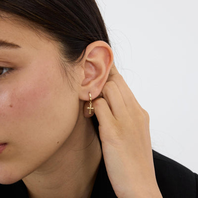 14K gold cross hoop earrings styled on a neutral backdrop, third angle