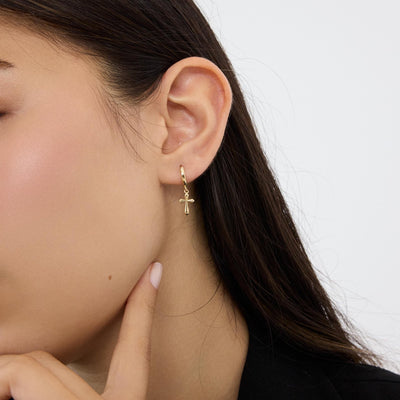 14K gold cross hoop earrings styled on a neutral backdrop, fifth angle