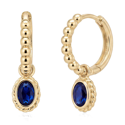 Pair of 14K yellow gold beaded huggie earrings with oval blue stone drops and twisted rope bezel