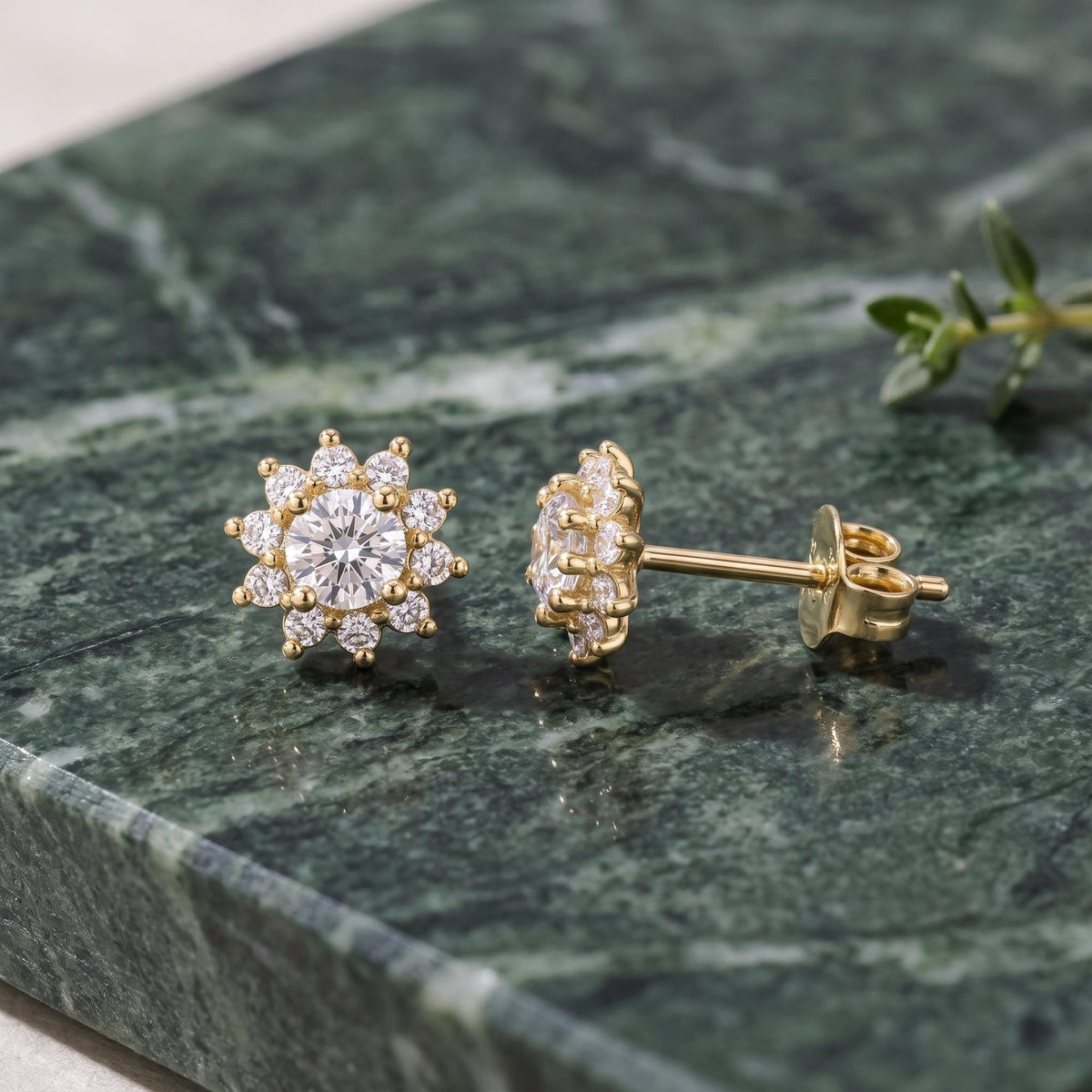 14K yellow gold cubic zirconia halo stud earrings, front and side view on green marble with a sprig