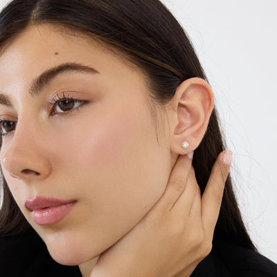 14K gold cubic zirconia halo stud earring worn on the ear, model with hand at jaw, close crop