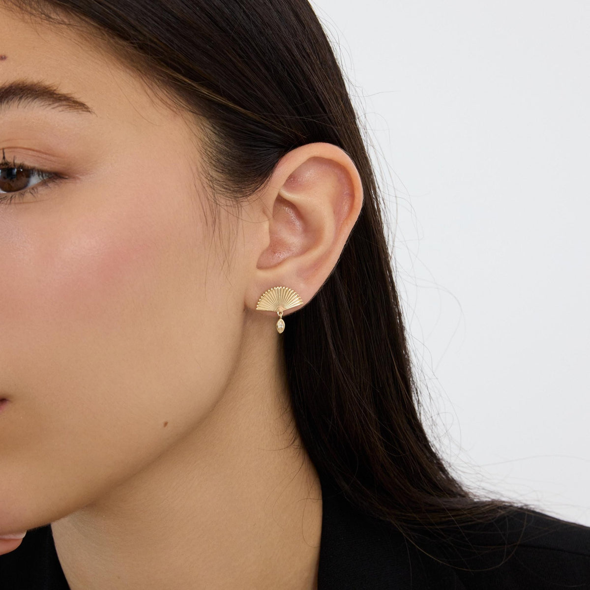 14K gold fan drop stud earring with marquise cubic zirconia worn in ear, woman in black top, wider crop