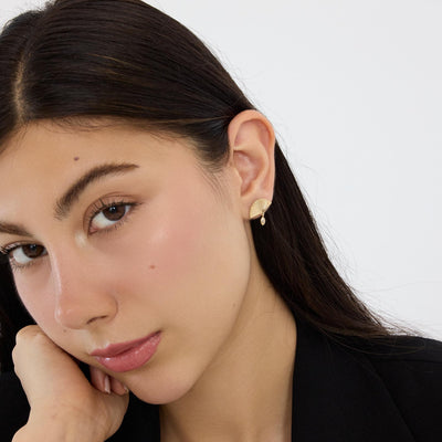 14K gold fan drop stud earring with marquise cubic zirconia worn on ear, model resting chin on hand