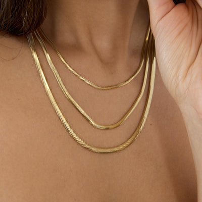 14K gold flat snake chain necklace styled on a neutral backdrop
