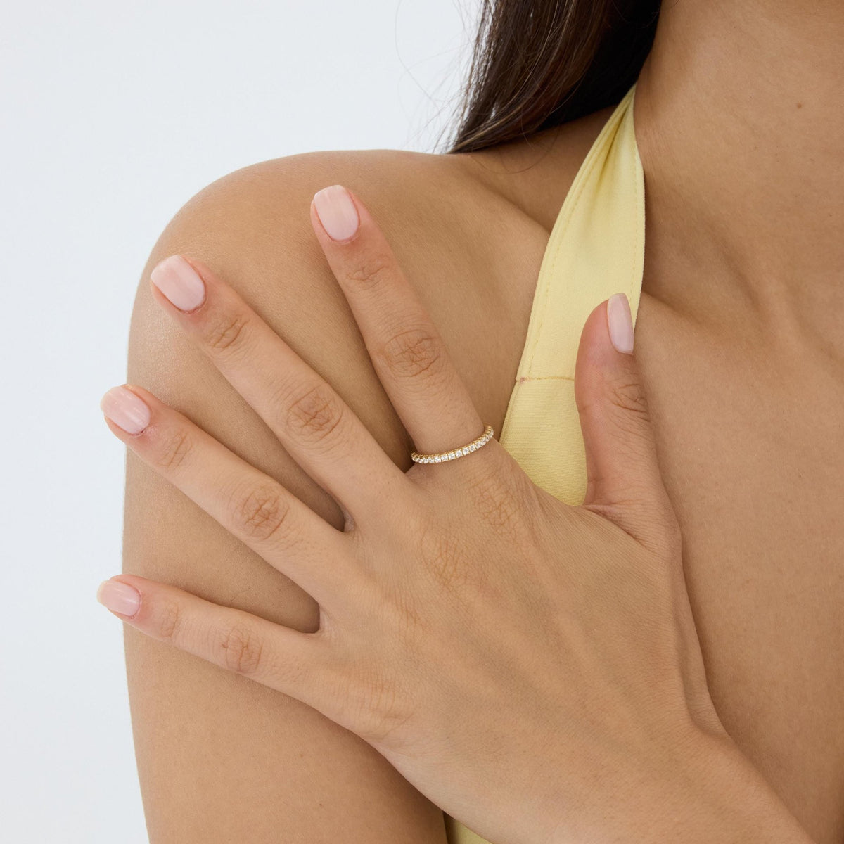 14K gold half eternity ring worn on the ring finger, hand resting on the model's bare shoulder